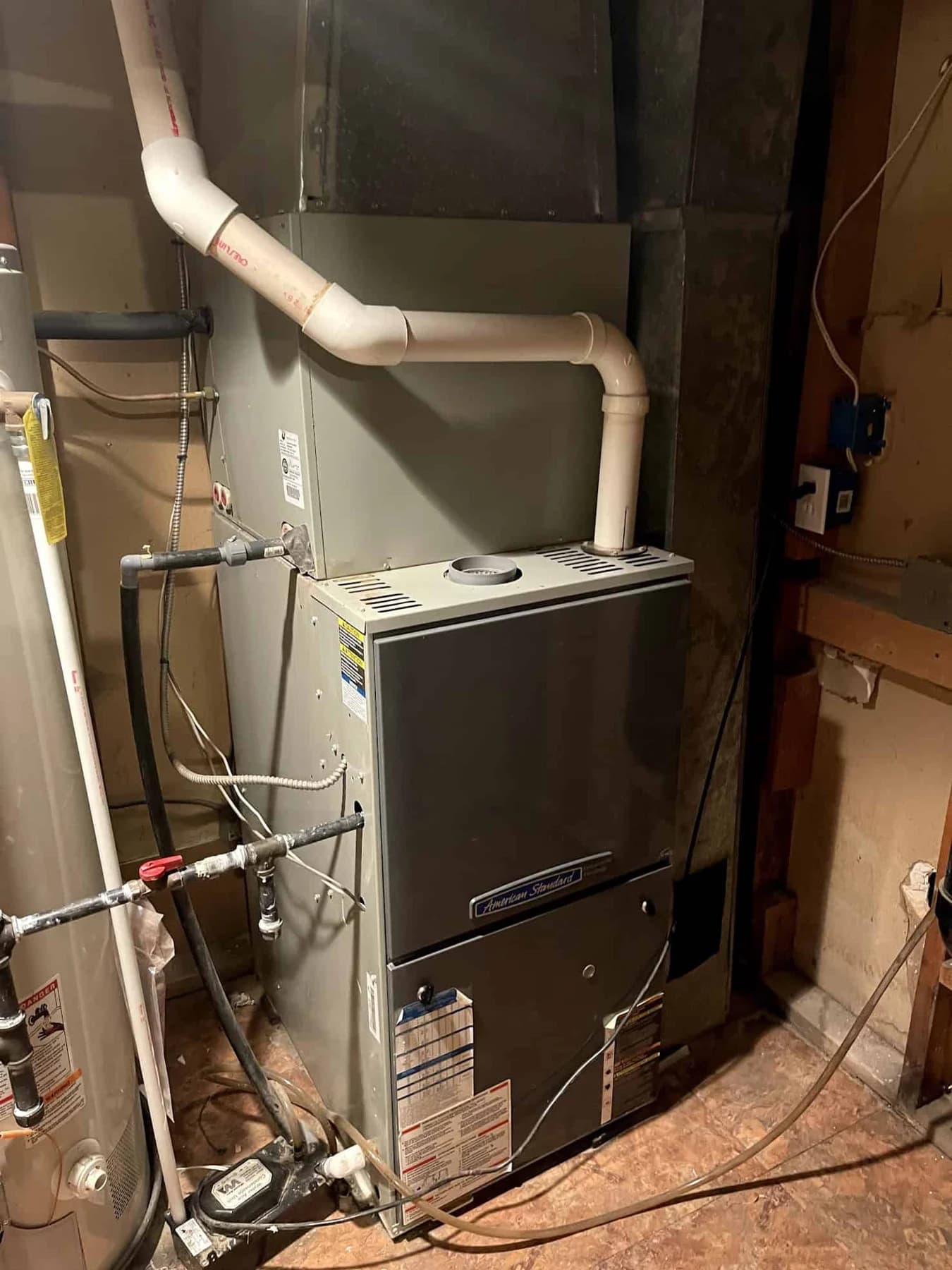American Standard furnace beside a water heater in an unfinished basement